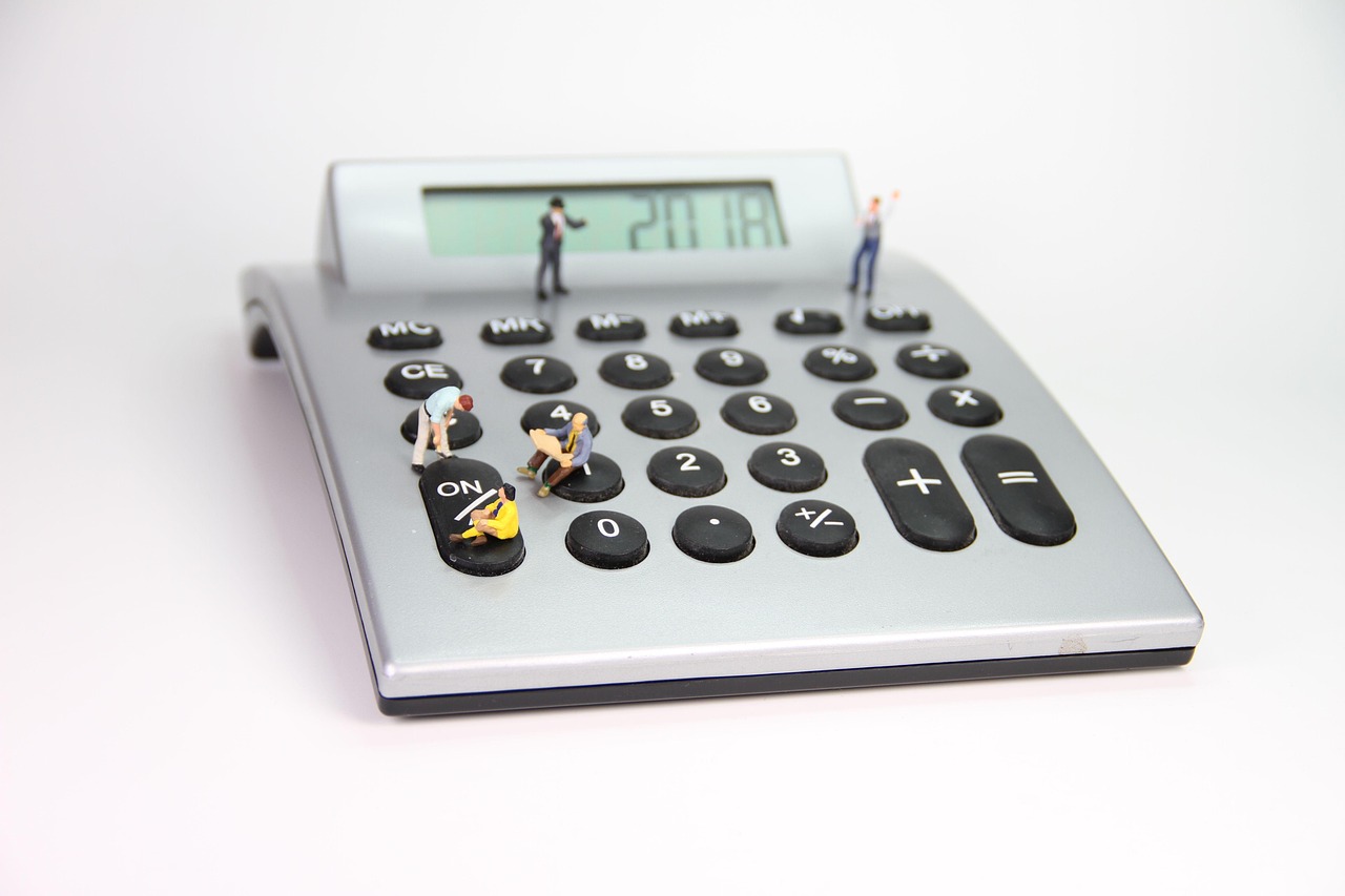 calculator with miniature people standing on the buttons
