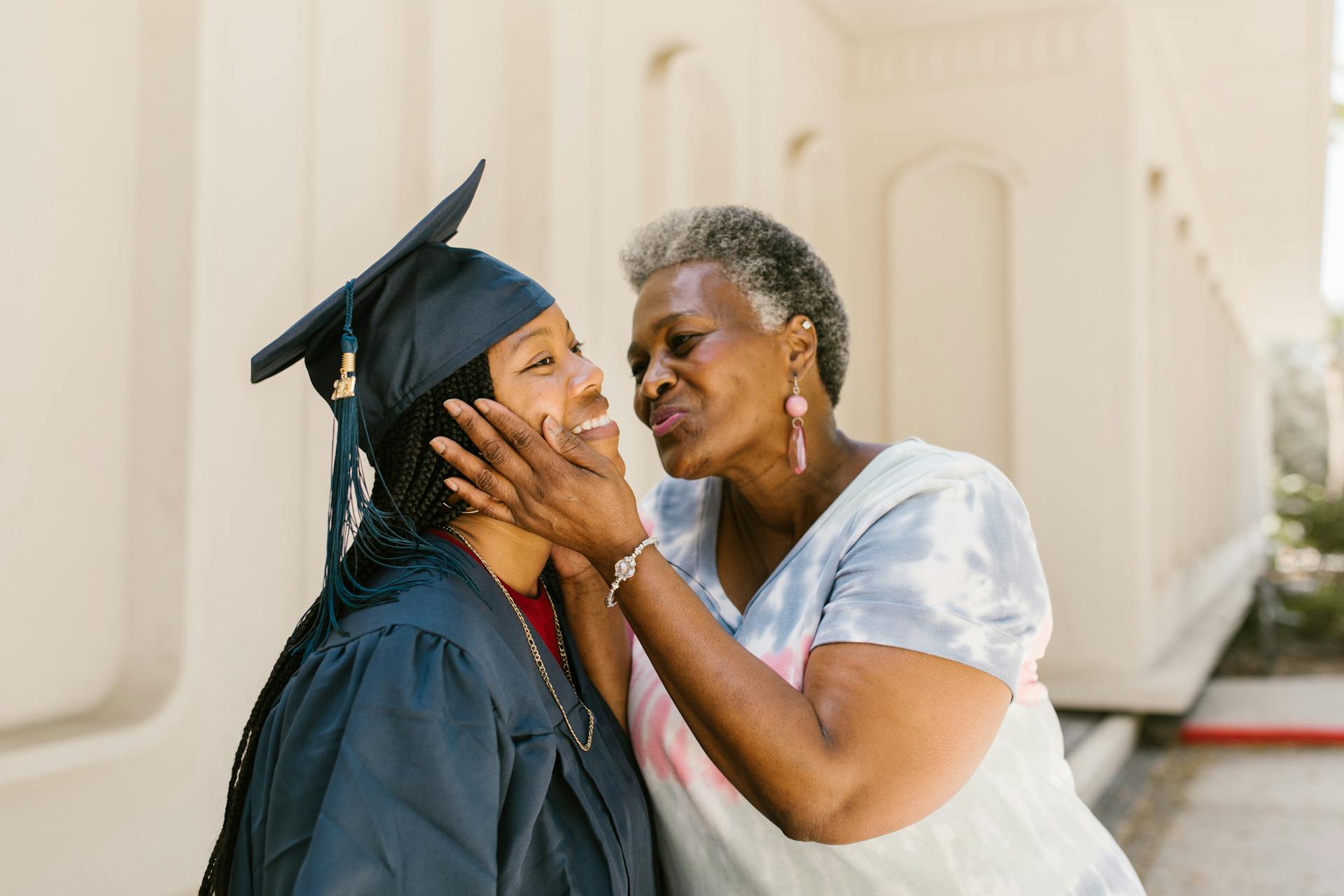 Parent kissing college graduates cheek