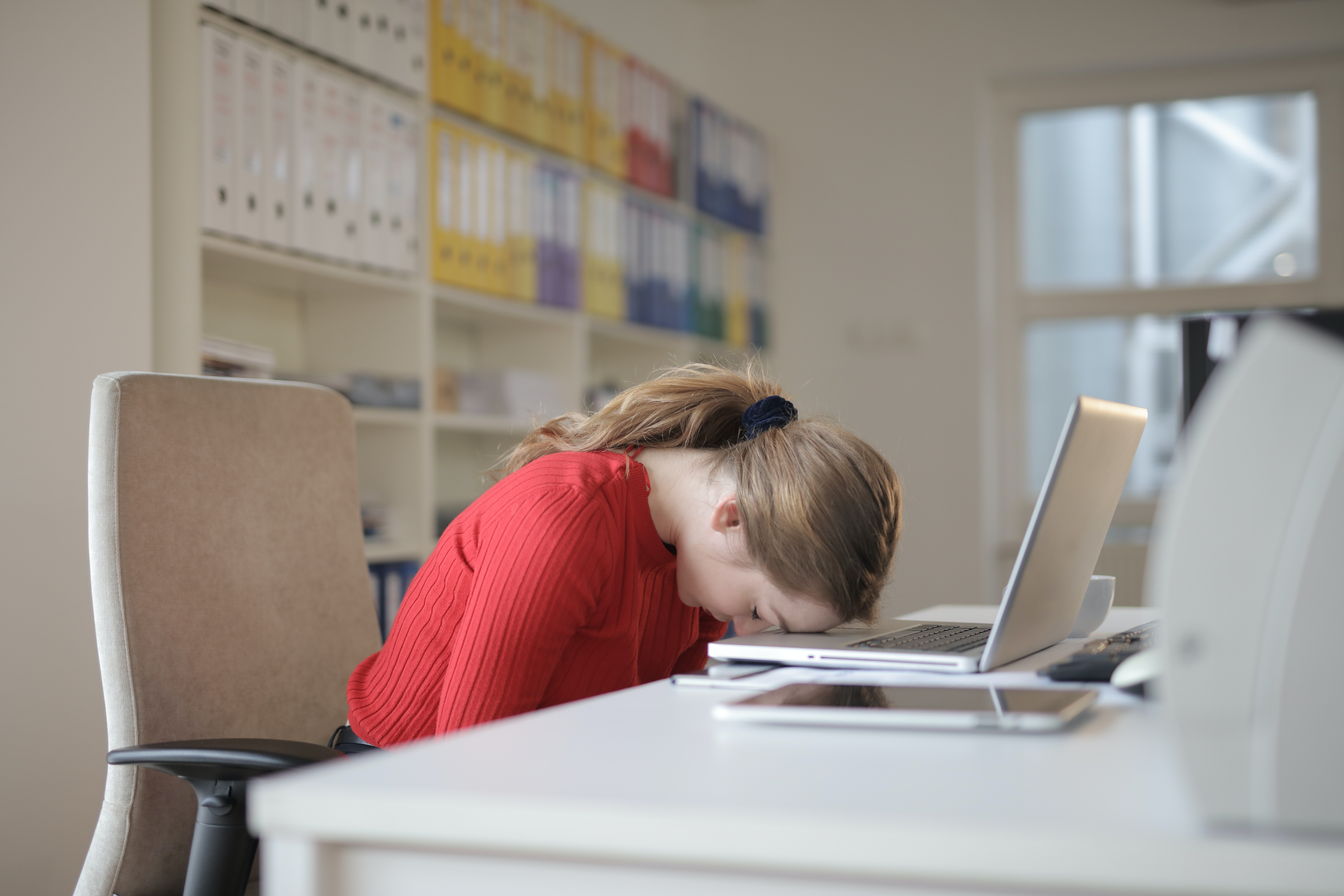 woman with head on desk at computer