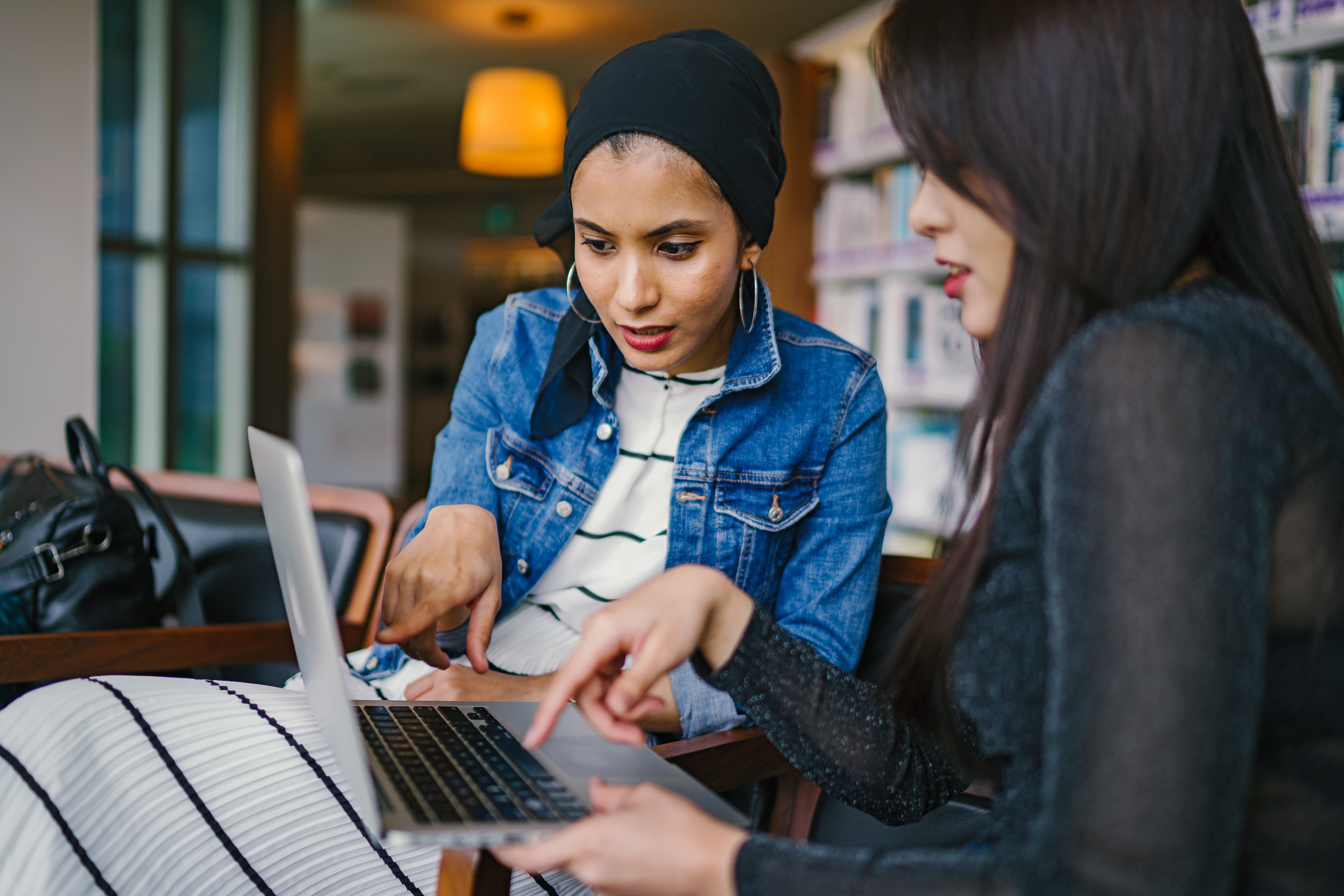 women pointing at laptop looking over taxes