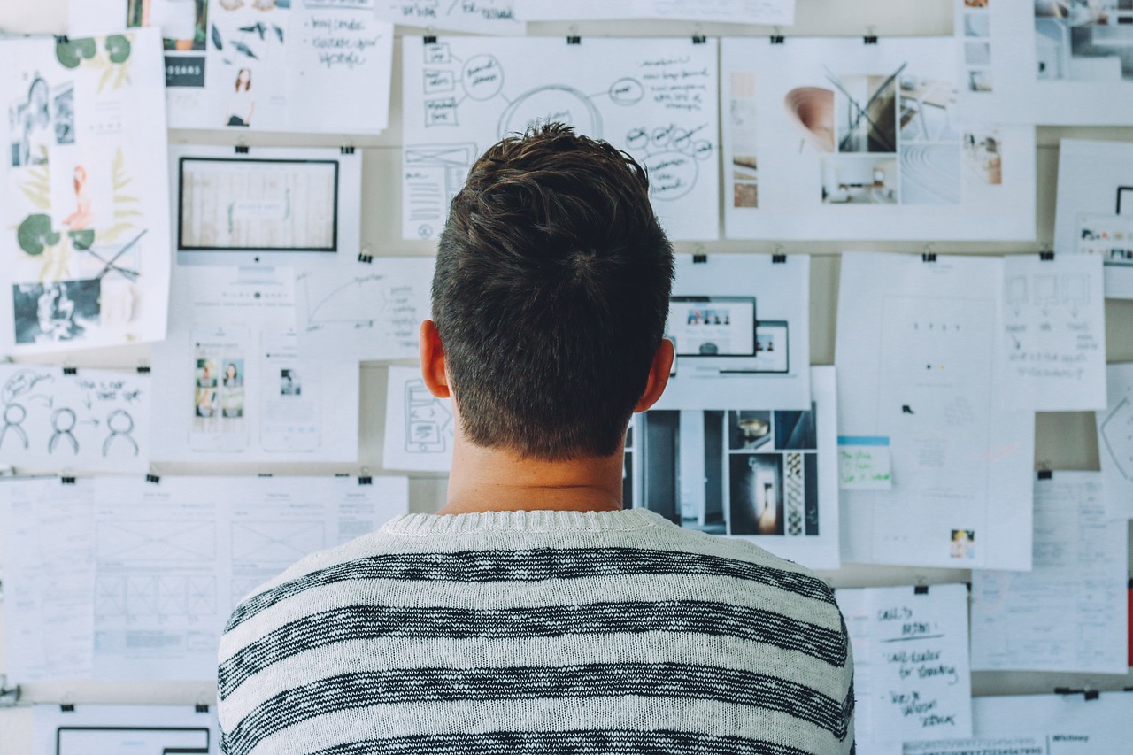 Man staring at bulletin board covered in work papers