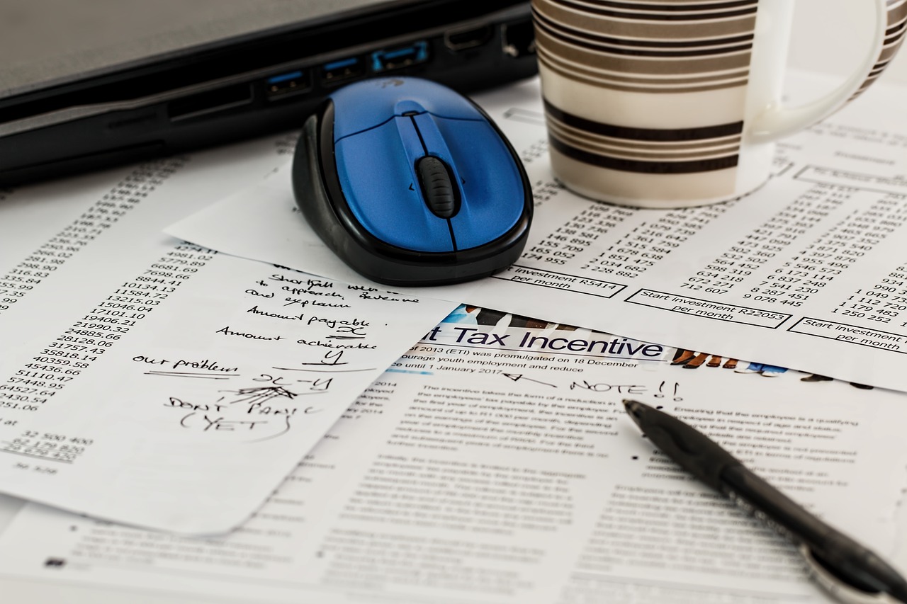 Computer mouse, mug, and tax paperwork on desk